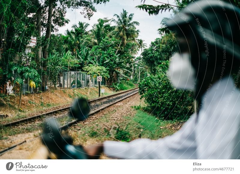 Man with mask on scooter in front of train tracks in Asia Railway tracks Transport Railroad Mask Mobility Railroad tracks rails Rail transport