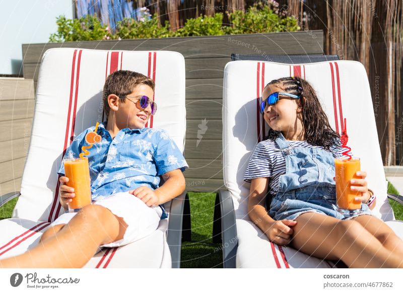 Two kids drinking orange juice on a hammocks boy calm caucasian child childhood citrus closeup day enjoy fresh garden girl glass glasses hang happy holiday