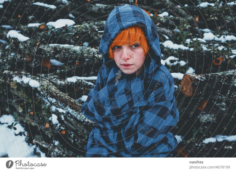 Redhead androgynous model in a winter scene people teen androgynious queer non-binary young youth cold hood hoodie redhead warm warmth thinkg alone wood