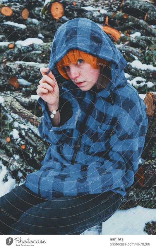 Redhead androgynous model in a winter scene people teen androgynious queer non-binary young youth cold hood hoodie redhead warm warmth thinkg alone wood