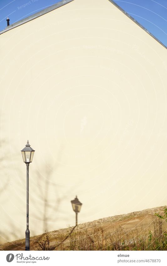 Street lamp and its shadow in front of or on the windowless gable end of a house / live / street lighting street lamp Shadow Shadow play dwell Gable end