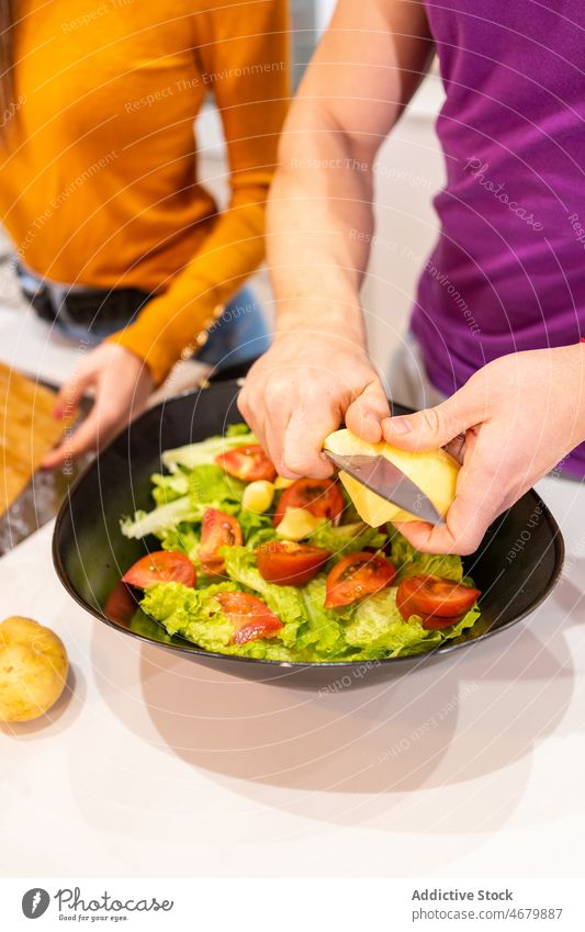 Anonymous man making salad near faceless woman couple kitchen cook food culinary homemade recipe cuisine cheese ingredient together at home light bowl