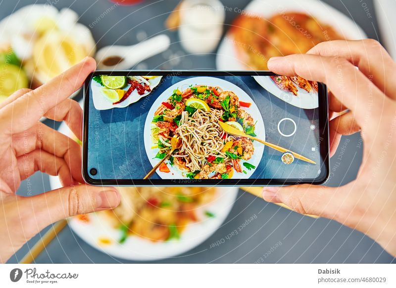 Taking photo of stir fry noodle with smartphone for social media food photography wok soba asian nutrition cuisine mobile pov restaurant recipe share kitchen