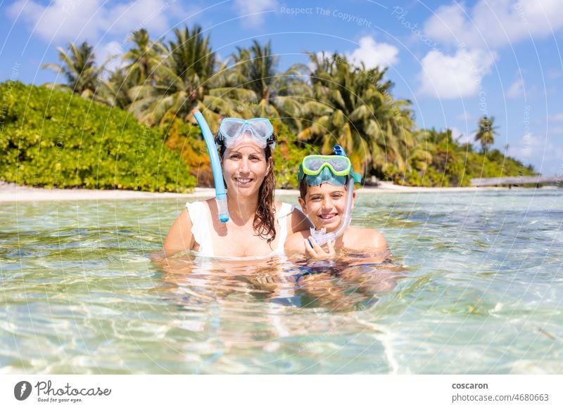 Mother and son snorkeling on a beach of the Maldive Islands bikini blue boy brunette candid caribbean child coast day fashion happy healthy indian ocean island