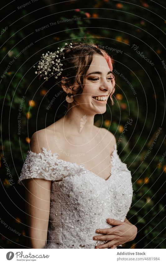 Young cheerful bride near bush in garden woman wedding smile shrub happy ceremony tradition romantic celebrate female delight dress stone summer elegant lush