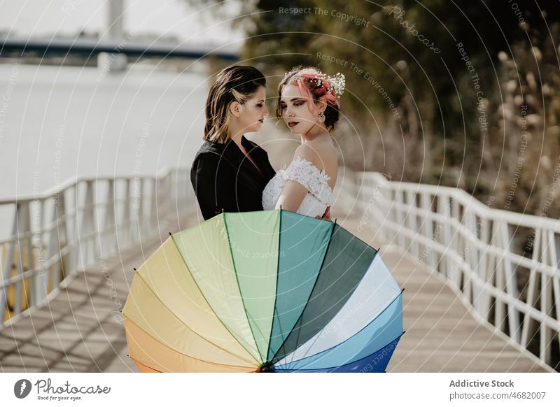 Brides embracing behind umbrella during wedding women bride love lesbian couple embrace park celebrate female together hug romantic bridal happy daytime partner