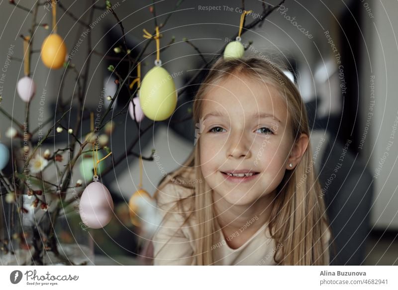 happy caucasian toddler girl eight years old at home in living room with colored easter eggs. Stay home during Coronavirus covid-19 pandemic holiday child kid