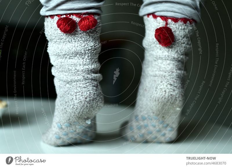 Southwest German table dance folklore on my white kitchen table with two feet on toes in white socks with bright red pom poms against dark background bobble