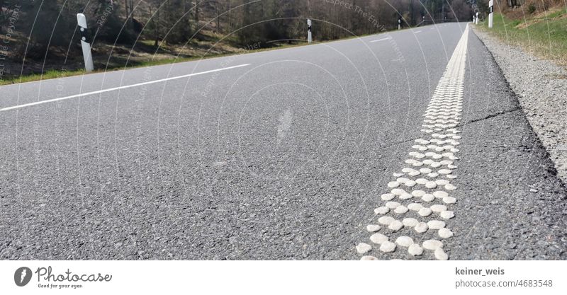 Asphalted road with studded acoustic lane markings. Quiet country road in Spessart with verge Street Country road Lane markings Traffic lane Pole Line nap