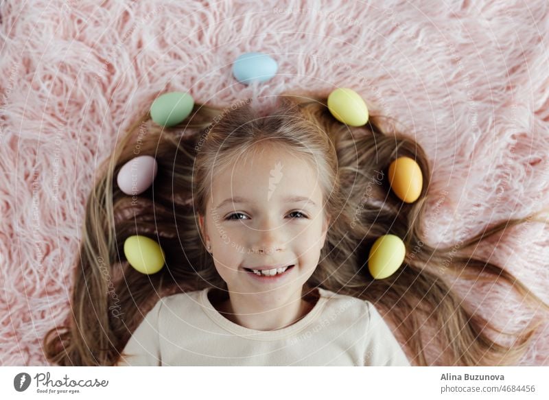 happy caucasian toddler girl eight years old at home in living room with colored easter eggs. Stay home during Coronavirus covid-19 pandemic holiday child kid