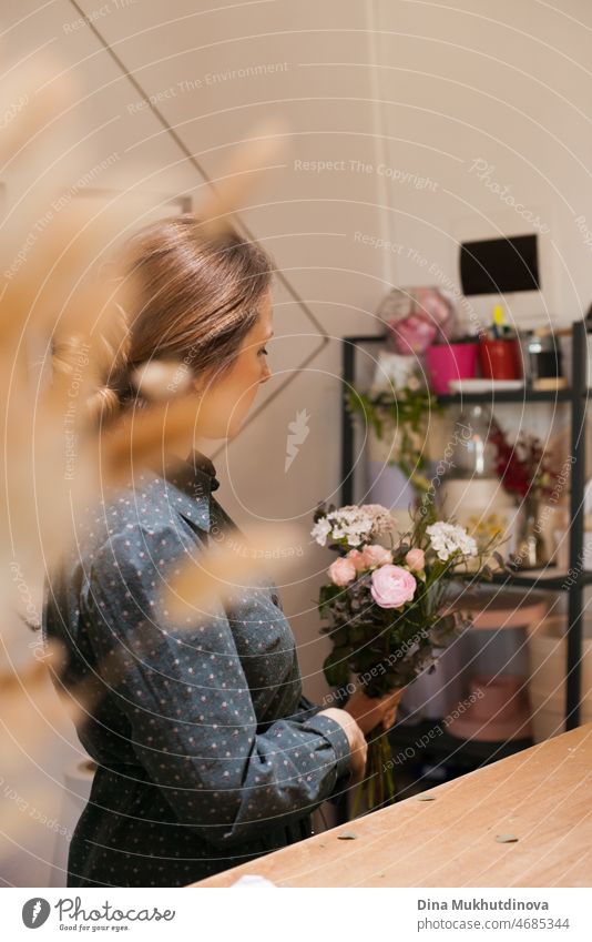 Woman florist making a bouquet at flower shop. Female floral artist working in her store - creative small business concept. workplace job blossom decoration