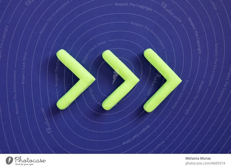 Green arrows pointing right side. Three dimensional arrow sign showing direction on blue background. Development  concept, go green or heading target metaphor, striving for the goal, going forward.