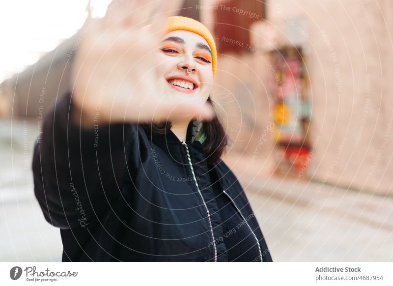 Cheerful woman showing stop gesture in city sign style informal street trendy design building sunlight lady young female fashion apparel sunshine appearance