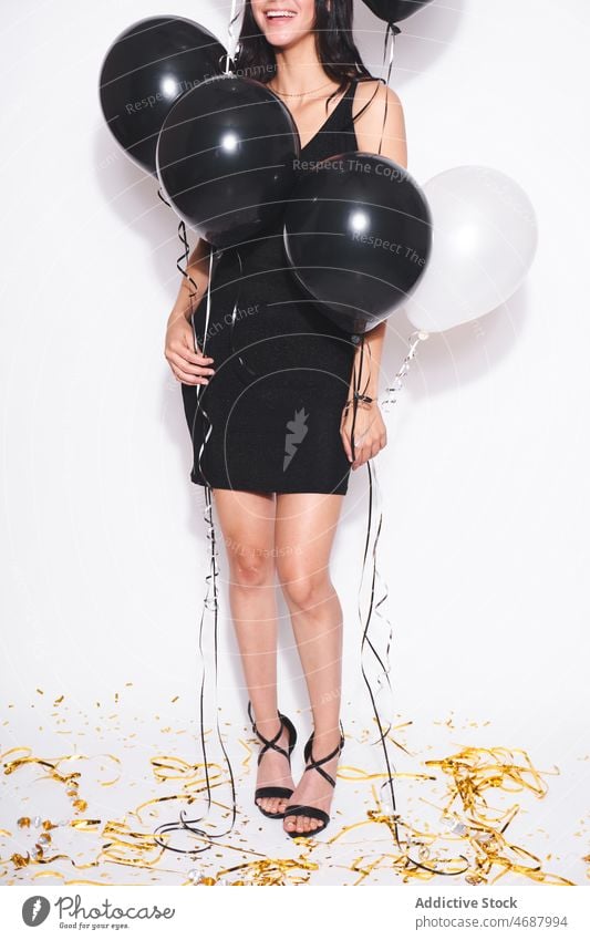 Anonymous attractive woman with black and white balloons birthday celebrate holiday style event festive smile fashion black dress feminine charming female happy