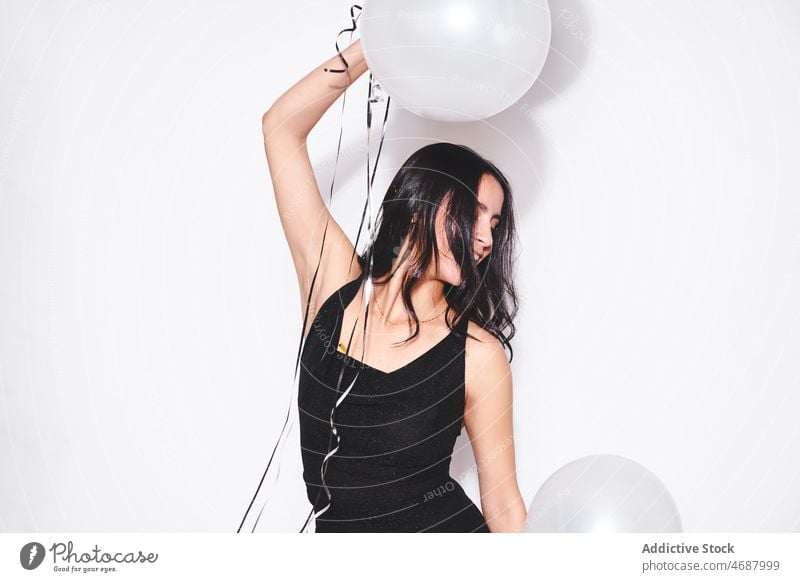 Attractive woman with black and white balloons birthday celebrate holiday style event festive smile fashion black dress eyes closed feminine charming female