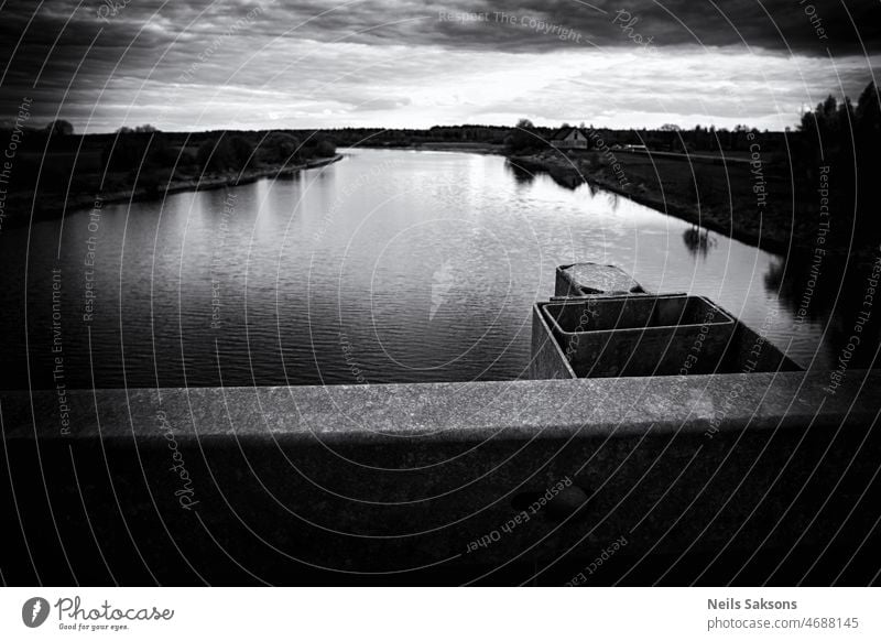 good place to stand and watch water flow. River Lielupe, Latvia, near Jelgava town. Dark pessimistic version river bridge railings above monochrome