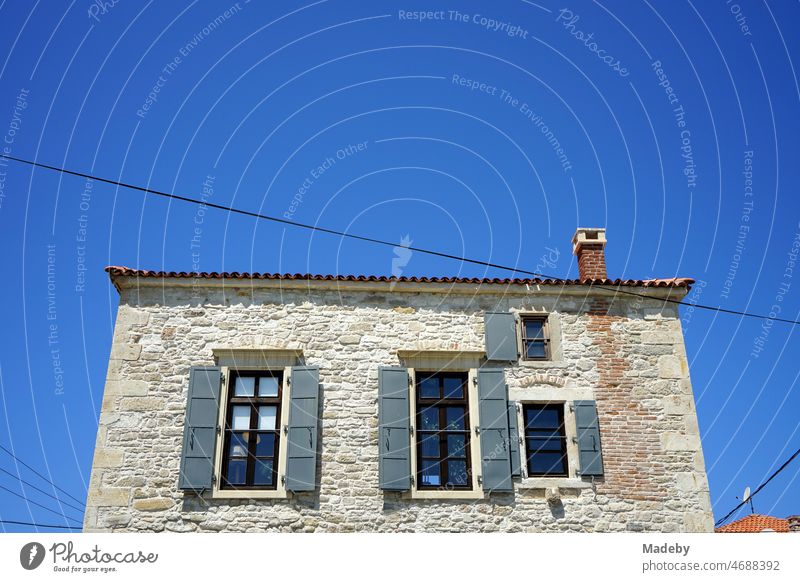 Old house with facade of natural stone in natural colors against blue sky in summer sunshine in Foca near Izmir on the Aegean Sea in Izmir province in Turkey