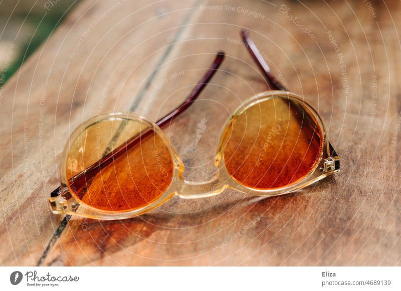 Colorful sunglasses in warm colors on wooden table Sunglasses Wood Wooden table variegated Summer Summer vacation summer atmosphere Orange Yellow