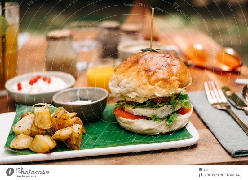 Burger with fried potatoes on a set table in the restaurant in the sunshine burger Restaurant Table Hash brown potatoes Fast food Lunch Hamburger Meal Delicious