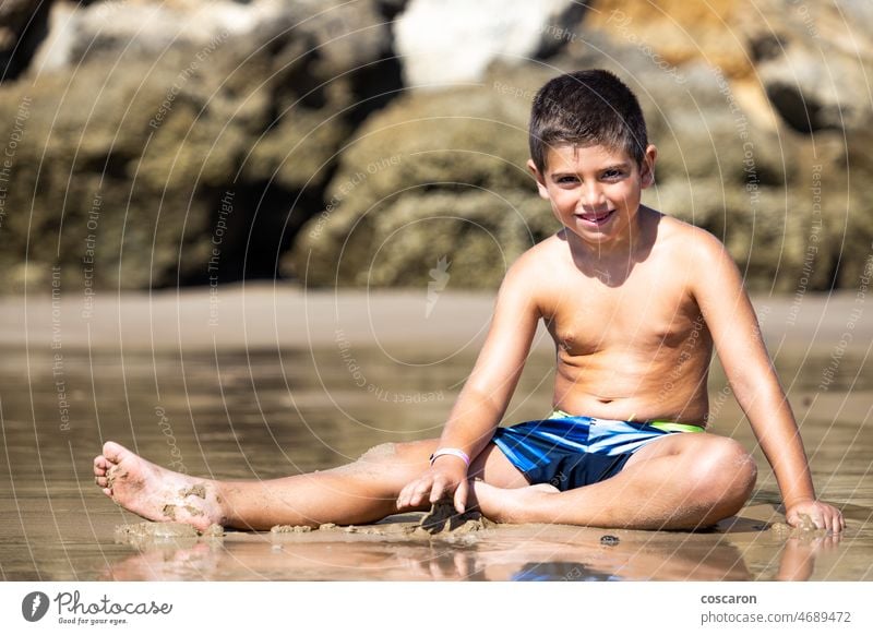 Little kid sitting on a rocky beach baby beautiful beauty boy cadiz cala del aciete calm caucasian child childhood conil cute funny happiness happy holiday