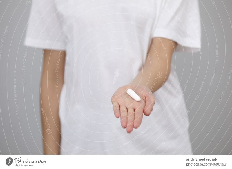 woman dressed in white t shirt, holding a clean tampon in her hands, close-up. female hygiene products, menstruation protection period girl disposable cotton