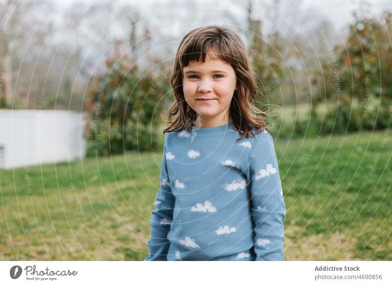 Cheerful girl in pajama walking on lawn street town hill childhood pastime kid building spend time grassy green environment glad area cheerful adorable