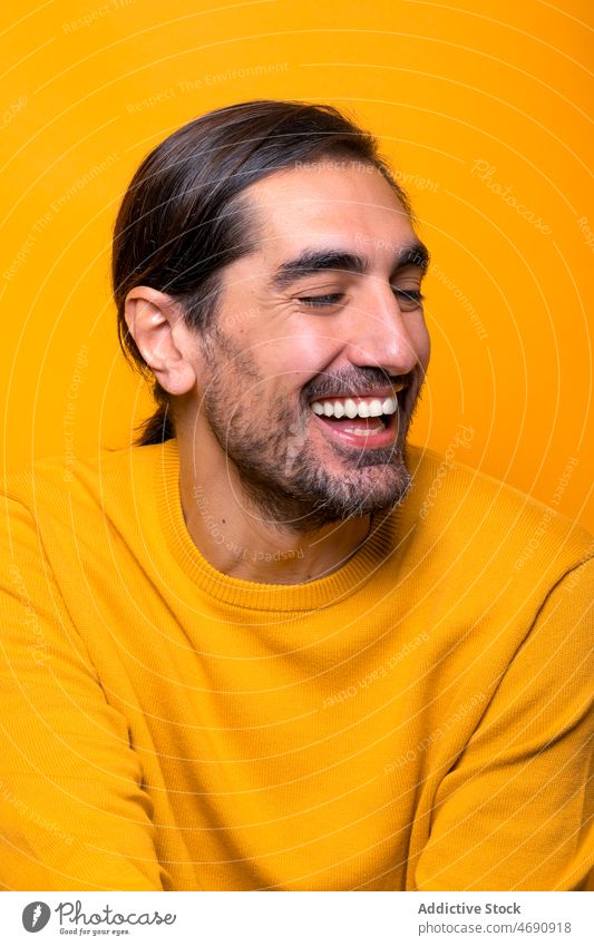 Cheerful man looking away in yellow studio carefree funny appearance silly mood playful beard portrait show male unshaven stare color gaze colorful light