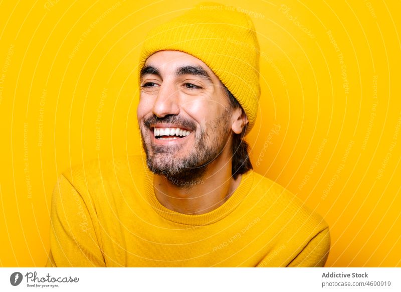 Cheerful man looking away in yellow studio carefree funny appearance silly mood playful beard portrait show male unshaven stare color gaze colorful light