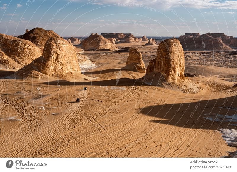 Automobiles driving through rocky formations in white desert arid nature national suv sand park dry heat location car destination scenery egypt africa vehicle