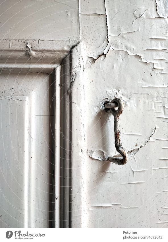 The small metal hook hangs on an old dilapidated door. He has been unemployed for many years, but his work has left traces on the door. Checkmark Metal bolt