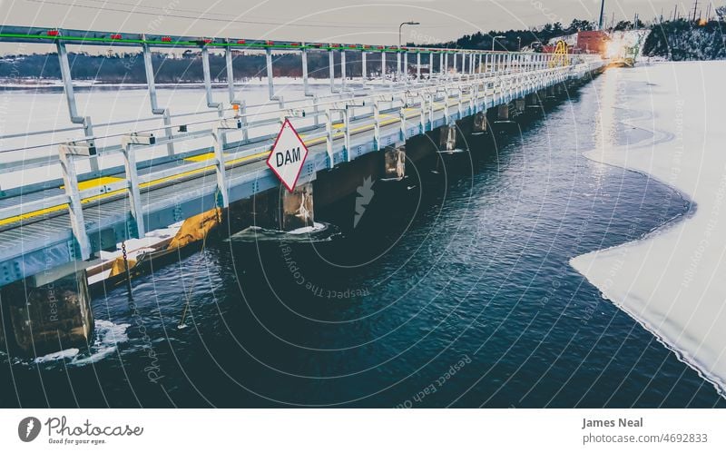 Snow covered dam on icy river at dusk frozen water matte ice cold railing winter path scene landmark frost day environment lake background structure