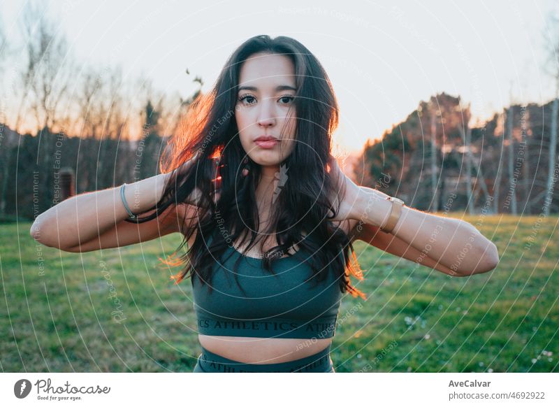 Young woman tying up their hair before starting running jogging outdoors on urban place. Training losing weight. African arab people doing exercise. Sunset colors