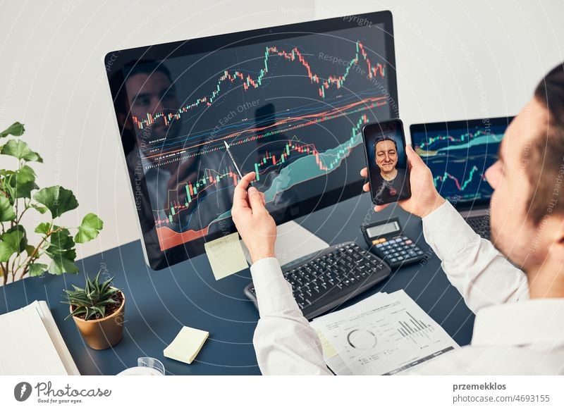 Businessman trading stocks online. Stock investor discussing numbers at graphs while video conversation with his colleague. Business team planning and analyzing stock market graphs. Business man investing stock online