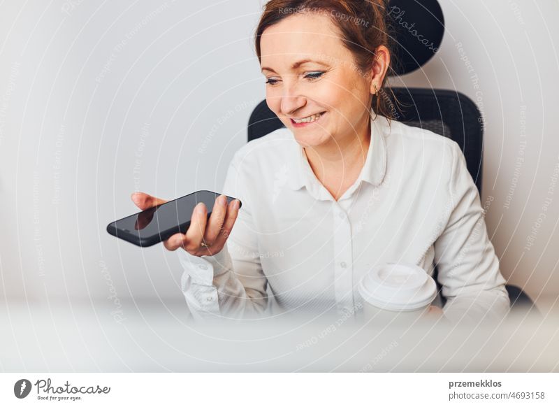 Businesswoman talking on mobile phone using speaker mode. Woman recording audio message using voice assistance and recognition function on smartphone business