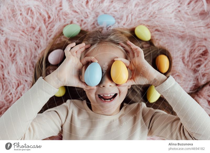 happy caucasian toddler girl eight years old at home in living room with colored easter eggs. Stay home during Coronavirus covid-19 pandemic holiday child kid