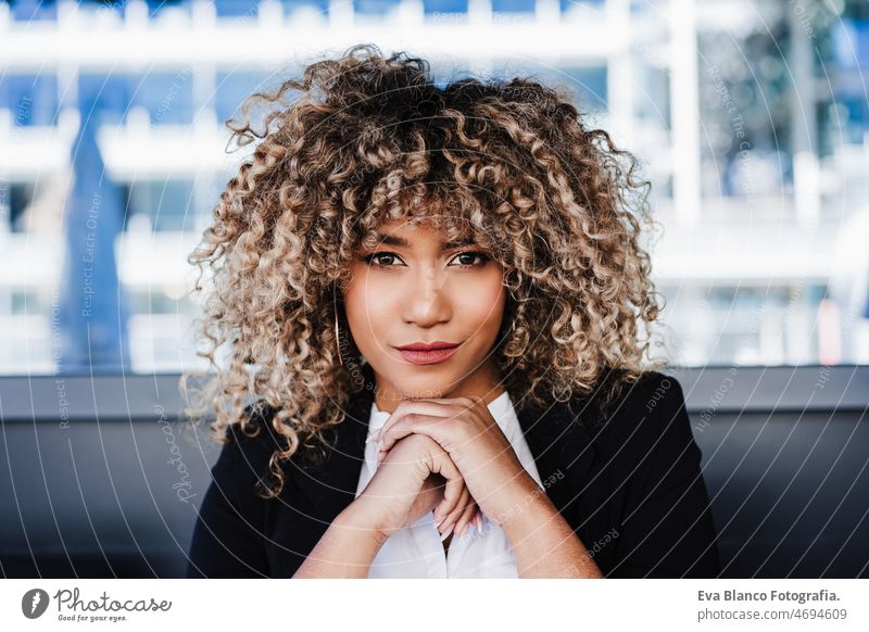 portrait of serious confident business woman in cafe. Business concept afro hispanic terrace smiling happy mobile phone city skyscraper building young