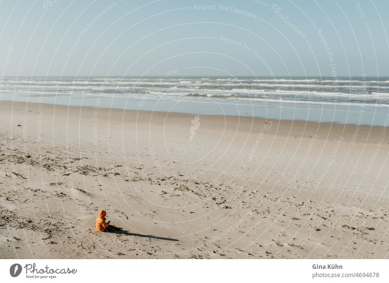 Child in yellow jacket sitting on beach Yellow Beach Ocean Winter Lonely by oneself Loneliness Shadow Anonymous 1 person Aurora Borealis coast Colour photo