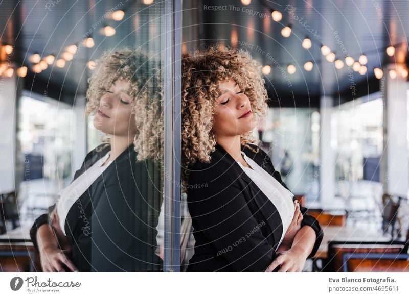 portrait of relaxed business woman with eyes closed in cafe leaning on glass. Business concept laptop computer afro working networking drinking coffee terrace