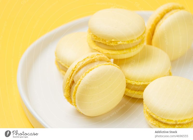 Pile of lemon macarons on plate dessert sweet confection confectionery indulge treat food flavor fresh tasty delicious yummy appetizing macaroon french bright