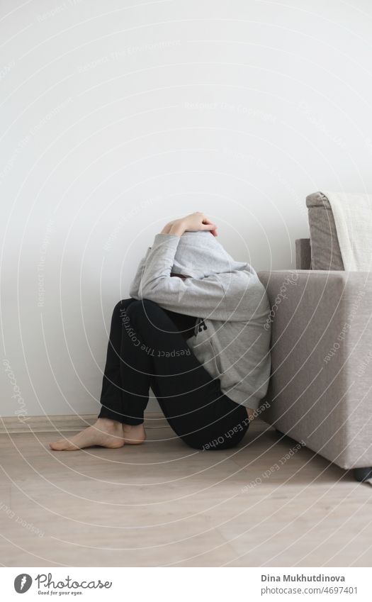 Depression, stress and anxiety - Person in black pants and gray hoodie sitting on the floor, desperate and sad. PTSD disorder and mental health, woman suffering. A person not being able to handle stress and anxiety, experiencing depression.