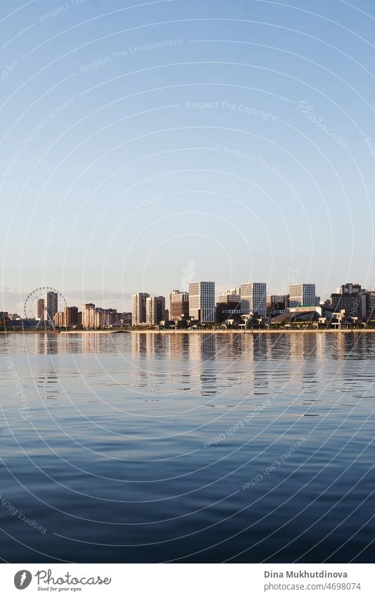 City skyline at sunset at blue hour. Cloudless sky, bridge reflected in river water. Urban cityscape reflection in water and modern architecture. Vertical urban summer background.