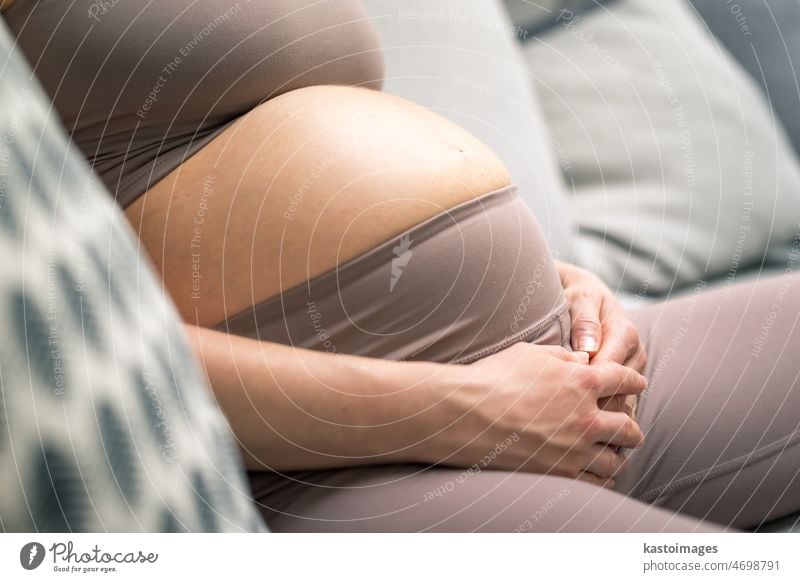 Pregnant woman belly. Pregnancy Concept. Pregnant tummy close up. Detail of pregnant woman relaxing on comfortable sofa at home. love beautiful expectant