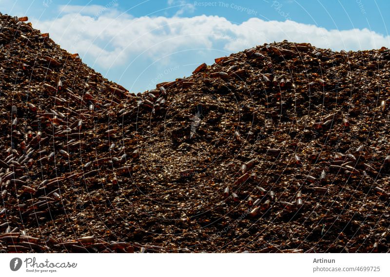 Pile of brown bottle for recycle in recycling factory. Glass waste for recycle. Dump of brown beer and wine glass bottle. Smashed glass bottle garbage. Recycling business. Sustainable glass packaging.