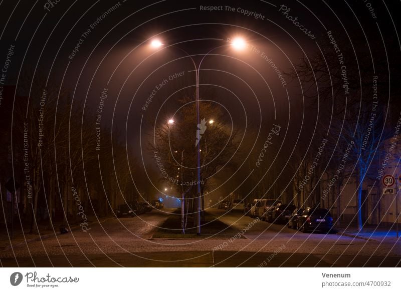 Germany,Luckenwalde, February 28, 2022,A little high fog at night under the street lamps Fog Foggy Mist Misty Street Streets Night Car Cars light post