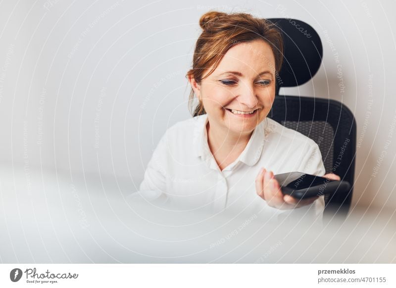 Businesswoman talking on mobile phone using speaker mode. Woman recording audio message using voice assistance and recognition function on smartphone business