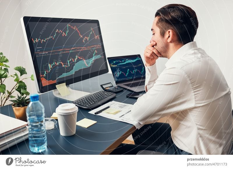 Worried businessman looking at charts stressed by news from stock market. Investor lost money online. Man analyses loss and profit. Businessman investing stocks online. Man working with stock chart data