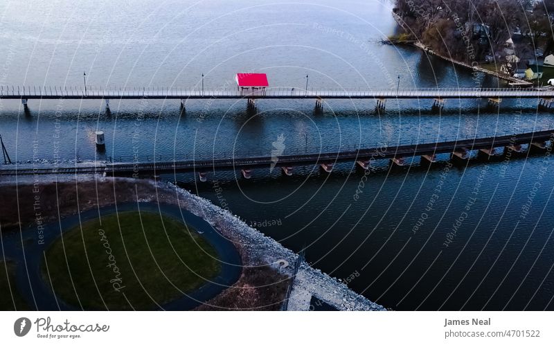 The red shelter of the trail stands out against the water landscape sunny color train track nature walking lake angle stones drone outside scenic outdoors