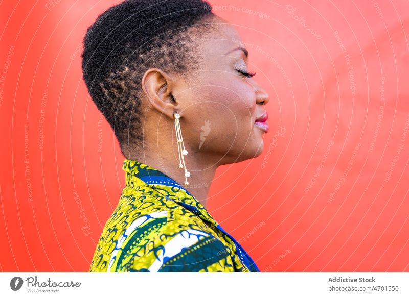 Positive black lady smiling while standing near bright wall woman smile self assured style model positive confident gorgeous cheerful portrait personality