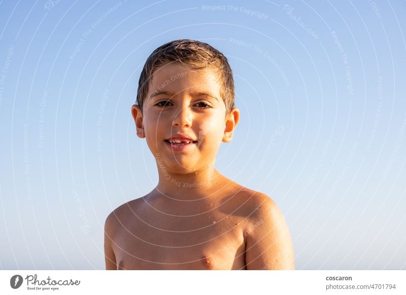 Portrait of a wet kid on a beach with a blue sky background adorable beautiful blond blonde hair boy caucasian child childhood concept cute evening face family