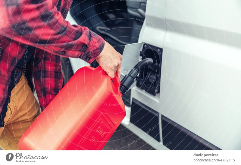 Unrecognizable man refueling his camper van with a jerrycan unrecognizable detail closeup maintenance combustible trip fill gas holding hand automobile